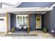 Inviting covered porch features seating, a yellow front door, dark gray siding, and manicured landscaping at 399 Chestnut St, Social Circle, GA 30025