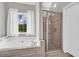 Bright bathroom featuring a soaking tub, tiled shower and a view of the green outdoors at 3135 Castlewood Dr, Loganville, GA 30052
