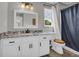 A well-lit bathroom with a white vanity with black hardware, a shower curtain, and wood accents at 3135 Castlewood Dr, Loganville, GA 30052