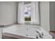 Modern bathtub with a bright window that looks out to a view of trees and blue skies at 3135 Castlewood Dr, Loganville, GA 30052