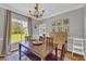 Traditional dining room with a wooden table and chairs, chandelier, and a large window overlooking a backyard at 3135 Castlewood Dr, Loganville, GA 30052