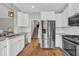 Bright kitchen boasts stainless steel appliances, subway tile backsplash, and beautiful hardwood floors leading to the stairs at 3135 Castlewood Dr, Loganville, GA 30052