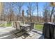 Outdoor patio with a table, chairs, umbrella, and grill, with a view of the wooded backyard at 4304 Lake Laurel Se Dr, Smyrna, GA 30082