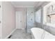 A bright bathroom featuring a glass walk-in shower, a soaking tub, and marble-style walls and floors at 821 Hood Rd, Fayetteville, GA 30214