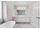 A bright bathroom with double sinks, a large mirror, soaking tub and marble-style floors and walls at 821 Hood Rd, Fayetteville, GA 30214