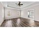 Spacious main bedroom featuring a tray ceiling, ceiling fan, hardwood floors and an attached bathroom at 821 Hood Rd, Fayetteville, GA 30214