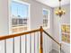 A staircase with white and oak banister, large windows providing natural light, and an elegant chandelier at 821 Hood Rd, Fayetteville, GA 30214