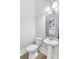 Powder room with a pedestal sink, a decorative mirror, and an energy efficient toilet at 212 Sessions St, Woodstock, GA 30188
