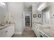 Well lit bathroom featuring double sinks, granite counters, tile floors, and walk-in closet at 5850 Overlook Rdg, Suwanee, GA 30024