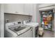 Convenient laundry room with white cabinets, washer, dryer, and shelving for organized storage at 5850 Overlook Rdg, Suwanee, GA 30024