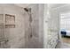 Elegant tiled shower with decorative niche and view into bathroom with granite vanity at 5850 Overlook Rdg, Suwanee, GA 30024