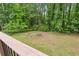 Backyard featuring lush green grass, wooded views, partially enclosed by a wooden railing, and surrounded by trees at 685 Maplelake Dr, Acworth, GA 30101