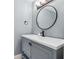 Modern bathroom vanity featuring gray cabinets, a round mirror, and stylish fixtures at 685 Maplelake Dr, Acworth, GA 30101