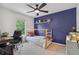 Bedroom featuring light colored carpet, blue accent wall, single bed, shelf with decor, ceiling fan, and natural light at 685 Maplelake Dr, Acworth, GA 30101