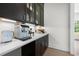Modern bar area featuring dark cabinets, white countertop, coffee maker, and beverage storage at 17145 River Overlook Dr, Roswell, GA 30075