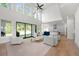 Open-concept living room with large windows, a fireplace, hardwood floors, and seamless access to the kitchen at 17145 River Overlook Dr, Roswell, GA 30075