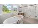 Bright bathroom with a soaking tub, walk-in shower, and serene views of nature at 17145 River Overlook Dr, Roswell, GA 30075