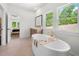Bright main bathroom with a standalone soaking tub, dual vanities, and large windows with a green view at 17145 River Overlook Dr, Roswell, GA 30075