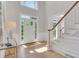 Elegant foyer with hardwood floors, a staircase with white railings, and natural light streaming in through the glass door at 6030 Sweet Creek Rd, Duluth, GA 30097