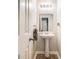 A charming half-bath with a pedestal sink, decorative towel, and neutral-colored walls at 3885 Weeping Willow Ln, Loganville, GA 30052