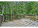 A nice wood deck with railing overlooks a lush green wooded backyard at 3885 Weeping Willow Ln, Loganville, GA 30052
