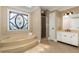 Luxurious bathroom with a soaking tub, tiled shower, custom vanity, and decorative stained glass window at 8260 Overview Ct, Roswell, GA 30076