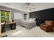 Cozy bedroom featuring a dark accent wall, desk, ceiling fan, and natural light from a window overlooking the trees at 8260 Overview Ct, Roswell, GA 30076