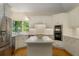 Open-concept kitchen with a central island, white cabinetry, stainless steel appliances, and natural light from a large window at 8260 Overview Ct, Roswell, GA 30076