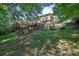 Backyard featuring wooden deck, patio, mature trees, and grass lawn on a sloping hill at 765 Vinings Estates Se Dr, Mableton, GA 30126