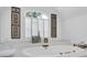 Bright bathroom with an oval soaking tub beneath a shuttered window and decorative wall art at 765 Vinings Estates Se Dr, Mableton, GA 30126