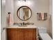Charming powder room with a granite countertop, wood vanity, and round decorative mirror at 1942 N Akin Ne Dr, Atlanta, GA 30345