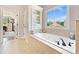 Large soaking tub in the main bathroom with window and built in storage shelves at 3456 Glen Mist Pl, Dacula, GA 30019