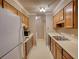Galley kitchen with wood cabinets, white appliances, and dated wallpaper at 107 Ridley Howard Ct, Decatur, GA 30030