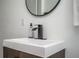 Bathroom features a sleek white sink with modern black faucet and round mirror on the wall at 1105 Gun Club Nw Rd, Atlanta, GA 30318