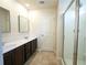 Bright bathroom with double sinks, dark wood cabinets, large mirrors, tile floors, and a glass-enclosed shower at 458 Bishop Ln, Woodstock, GA 30188