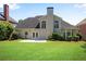 Expansive backyard features a well-manicured lawn and a rear facade with large windows, French doors, and lush landscaping at 4769 Ellington Ct, Marietta, GA 30067