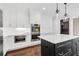 A white kitchen with dark island and stainless steel appliances under pendant lights provides lots of storage space at 4769 Ellington Ct, Marietta, GA 30067