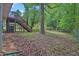A spacious backyard featuring mature trees and an elevated deck with access stairs at 5295 Old Trail Cir, Stone Mountain, GA 30088