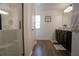Bright bathroom featuring double sink vanity with dark cabinets, wood-look floors, and a glass shower enclosure at 109 Auburn Crossing Dr, Auburn, GA 30011