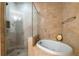 Spa-like bathroom with a soaking tub, glass-enclosed shower, and neutral tile at 2828 Peachtree Nw Rd # 1501, Atlanta, GA 30305