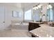 Bright bathroom showcasing a tiled soaking tub, vanity with granite counters, and a decorative mirror at 440 Scott Farm Dr, Powder Springs, GA 30127