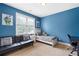 A cozy bedroom with a blue wall, featuring natural light, a comfortable lounge, and a desk area at 440 Scott Farm Dr, Powder Springs, GA 30127