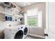 Well-lit laundry room with washer, dryer, shelves, and bright window at 440 Scott Farm Dr, Powder Springs, GA 30127