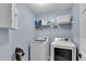 Bright laundry room with washer, dryer, shelving, and cabinet with blue painted walls at 562 Poplar Bnd, Canton, GA 30114