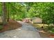 Exterior shot of the home from the gravel driveway, surrounded by trees at 6670 George Ct, Cumming, GA 30041