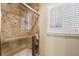 Bathroom shower with tile surround, glass door, and shuttered window at 3456 Drayton Ne Dr, Roswell, GA 30075