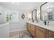 Bright bathroom features wood vanity with double sinks, marble countertop, and modern light fixtures at 503 Bonnie Dr, Woodstock, GA 30188