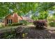 Well-manicured front yard with a brick home, mature trees, and an inviting bench for relaxing outdoors at 503 Bonnie Dr, Woodstock, GA 30188