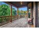 View of a covered back porch with wood decking overlooking a lush green landscape and mature trees at 1023 Bentley Estates Dr, Dacula, GA 30019