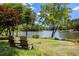 Backyard featuring lush grass, mature trees, and two wooden chairs facing the lake at 635 Stone Harbor Sw Pkwy, Marietta, GA 30060